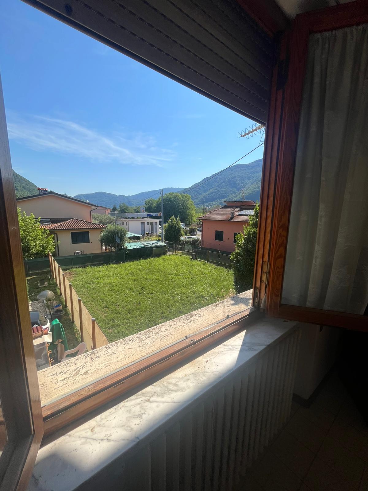 La vista dalla finestra della casa di Diecimo: giardino, tetti e colline sullo sfondo.